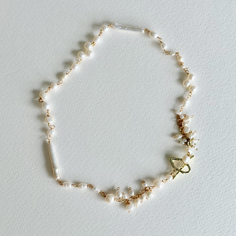 Delicate pearl necklace with gold accents on a light gray background
