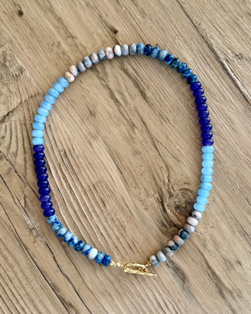 Full view of Violet Hour mixed gemstone necklace with color-blocked cobalt, violet, aqua and marbled jasper rondelle beads, finished with a gold toggle clasp.