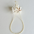 A beaded necklace with a white coral shell pendant, displayed on a textured off-white background.