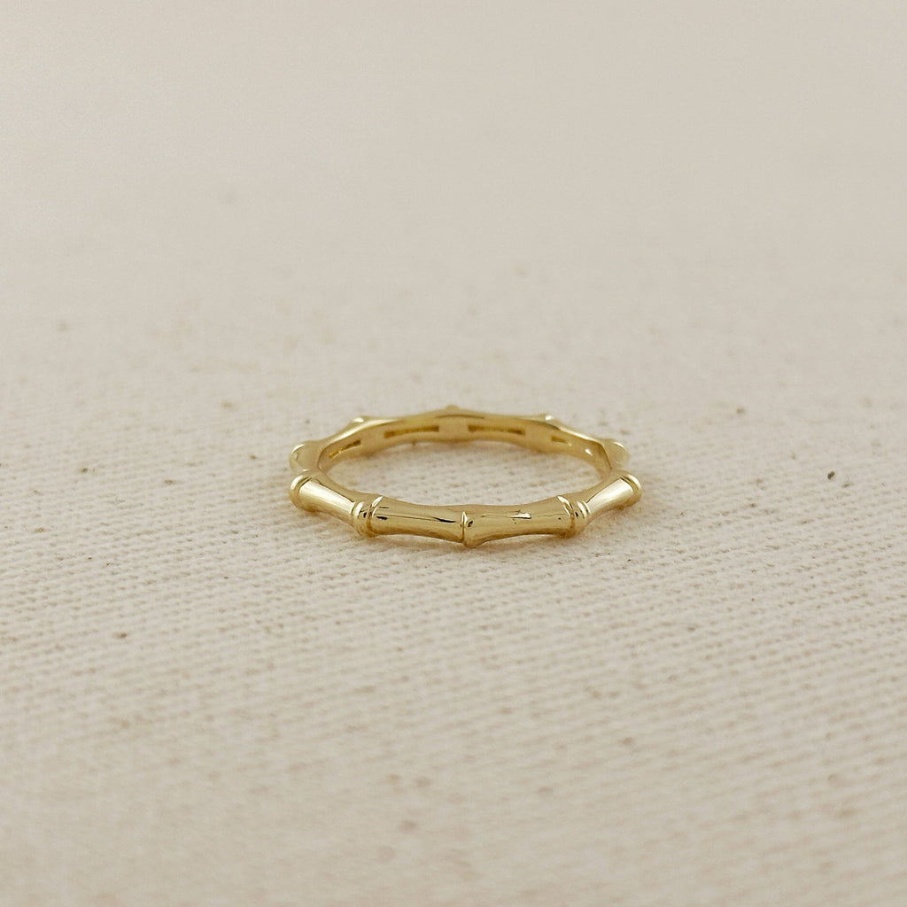 Gold ring with bamboo design on a beige fabric background