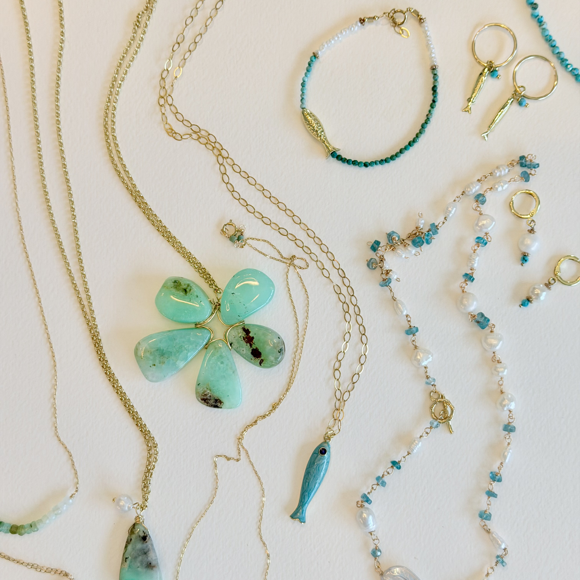 Collection of jewelry including necklaces, bracelets, and keychains on a light background