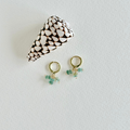 Pair of gold earrings with green beads on a light gray background