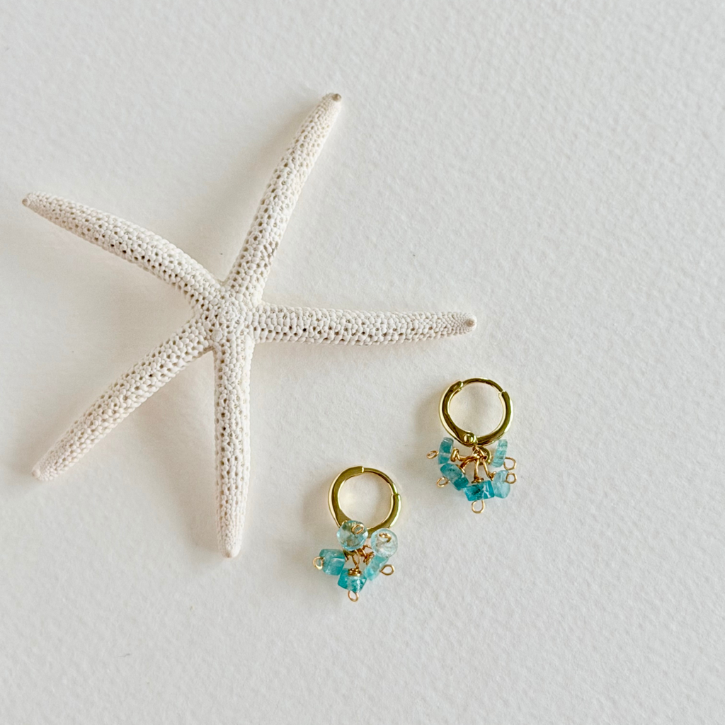 Gold and aquamarine earrings with a starfish on a light background