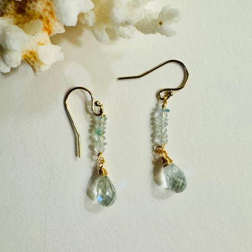 Gold earrings with green teardrop beads on a white background