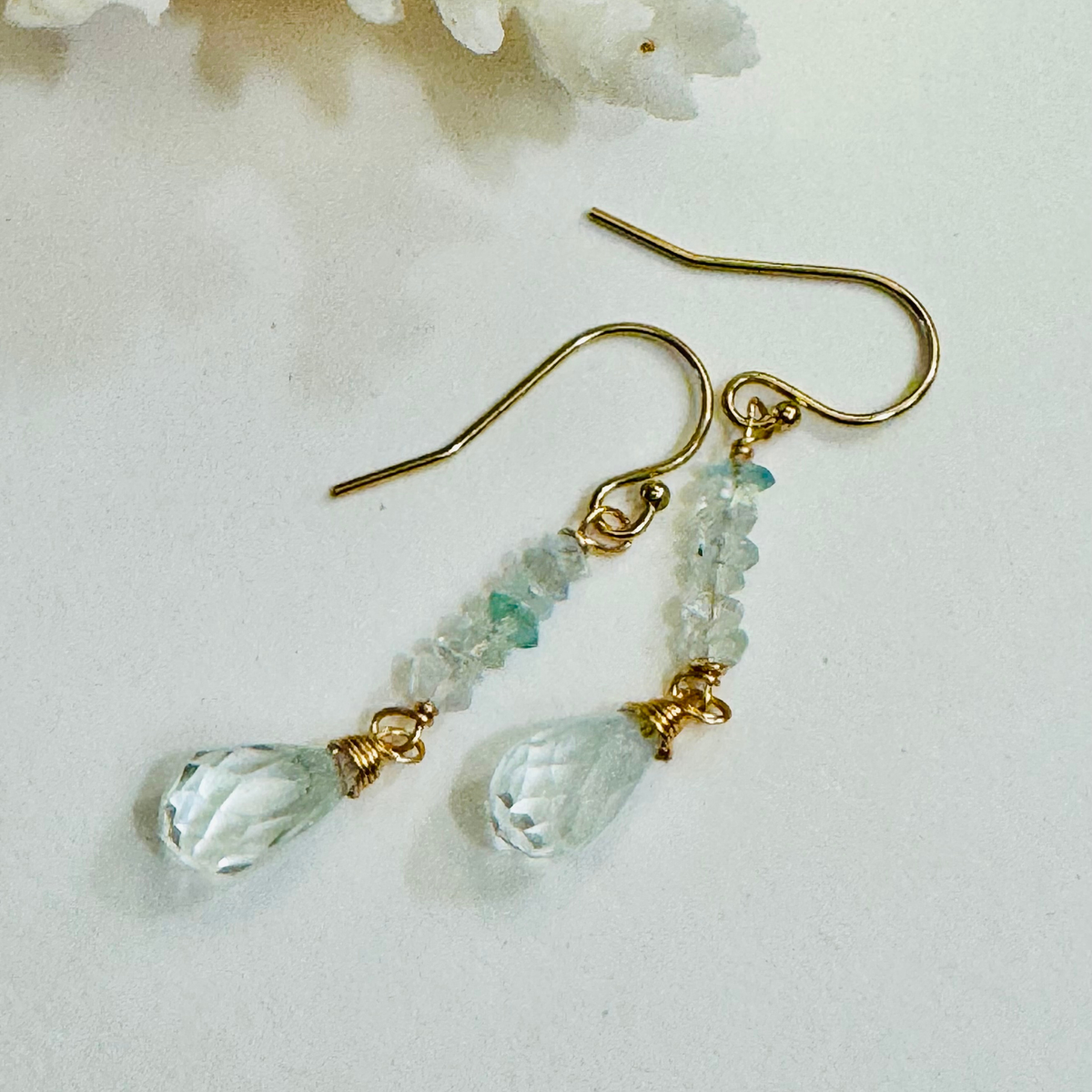 Gold earrings with green teardrop beads on a white background