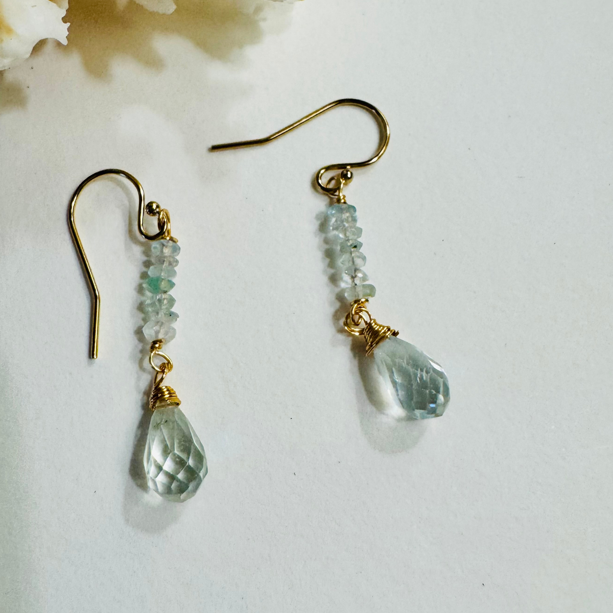 Pair of gold and green beaded earrings on a white background