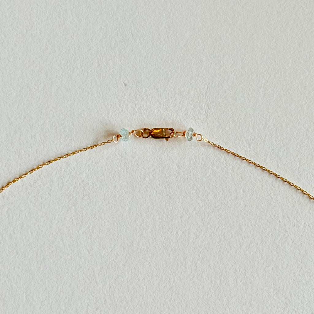 Gold bracelet with small beads on a light gray background