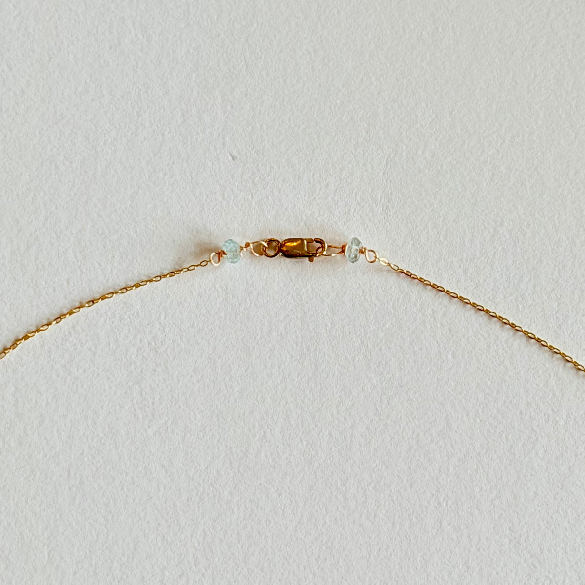 Gold bracelet with small beads on a light gray background