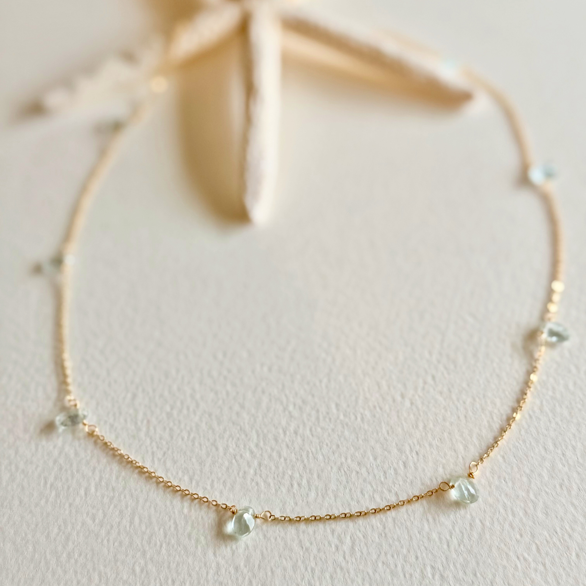 Delicate gold necklace with small pearls on a light background