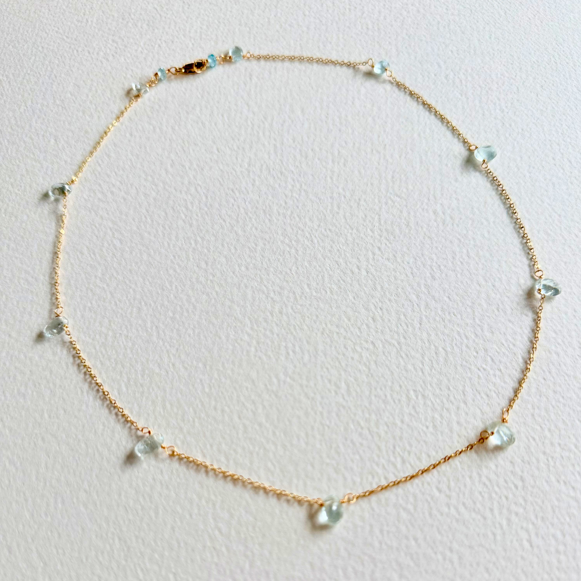 Delicate gold necklace with small beads on a light gray background