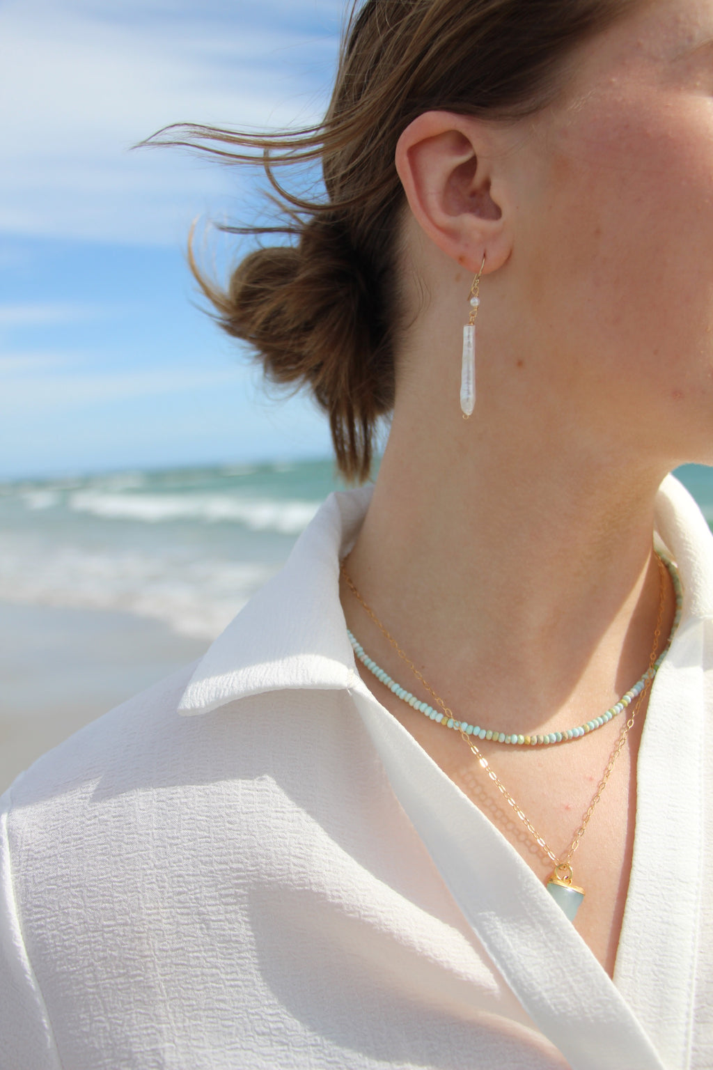 Person wearing earrings with a beach in the background