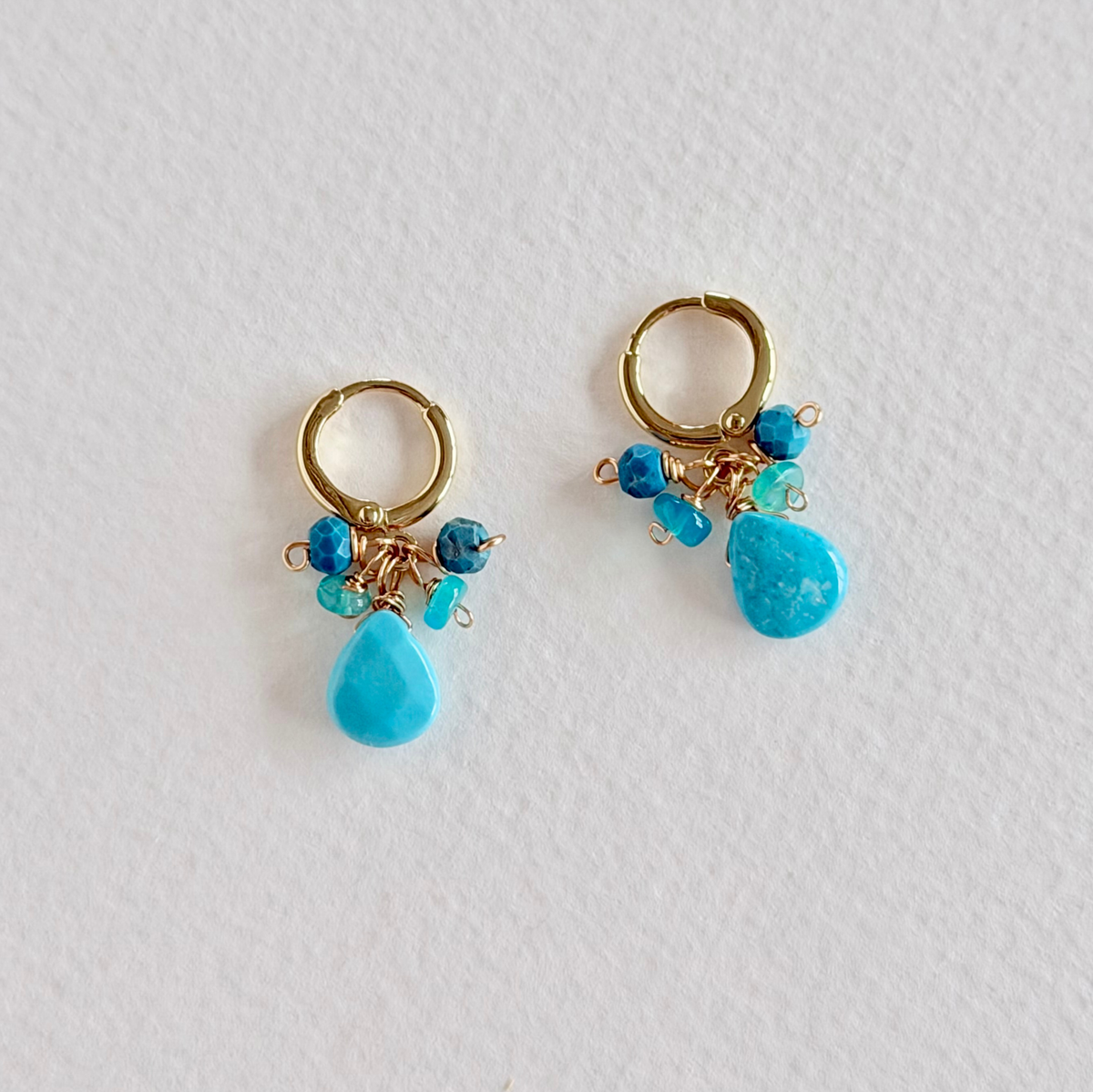 Gold hoop earrings with turquoise beads on a white background