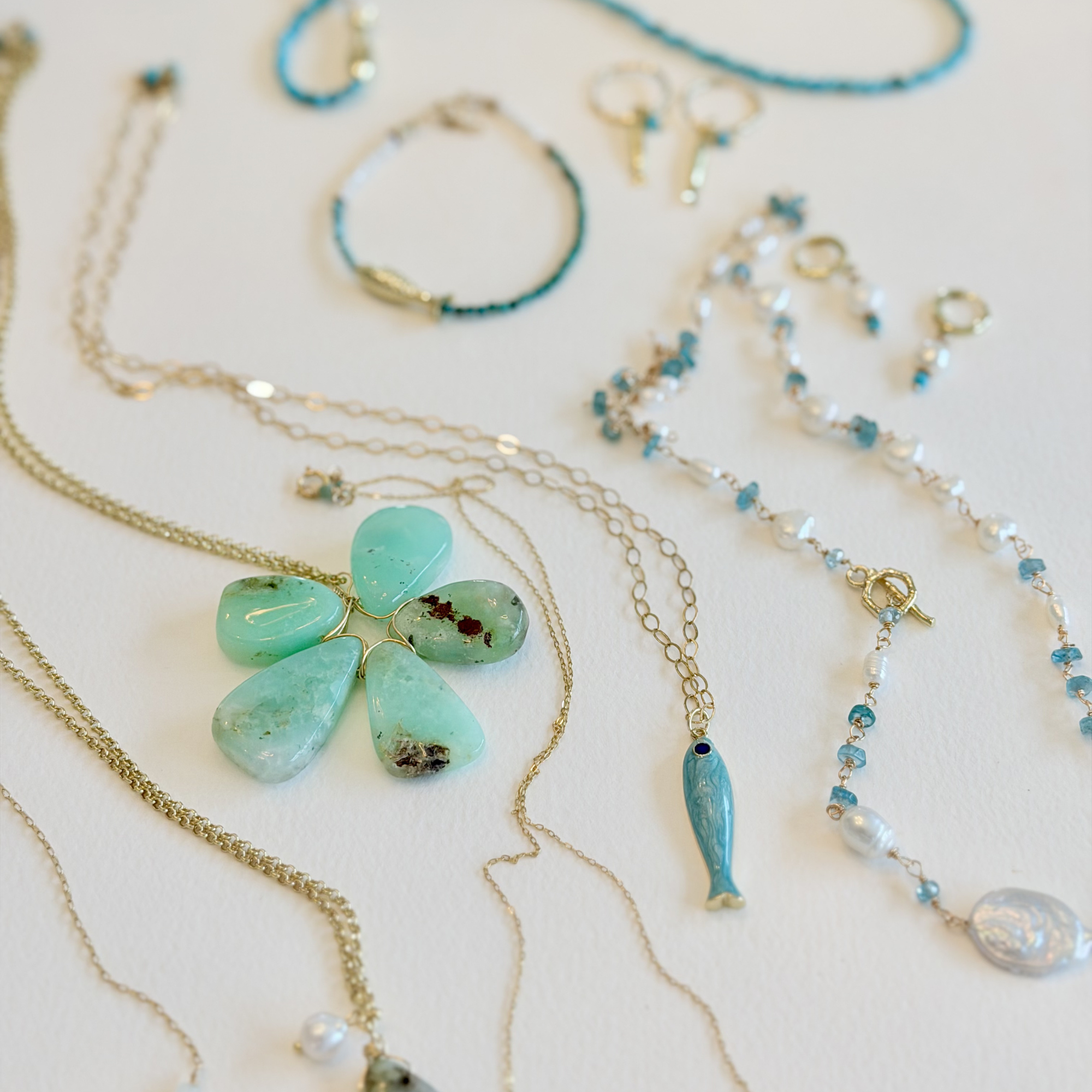 Jewelry set with turquoise flower pendant and beaded necklaces on a light background