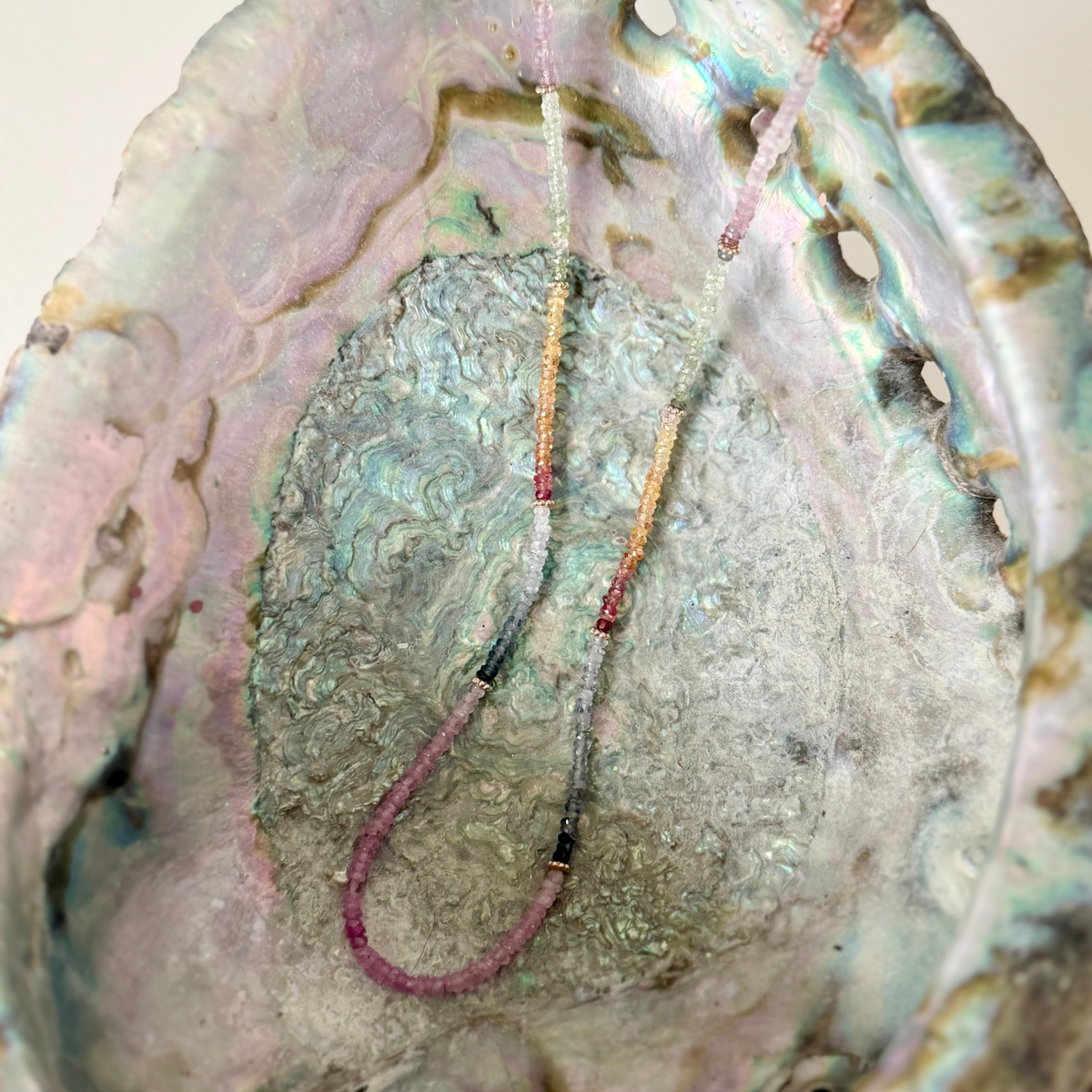 multi colored sapphire necklace on an abalone shell