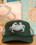 Dark green trucker hat featuring an original hand-painted blue crab in coastal blue and aqua tones by Marie & Oakley.