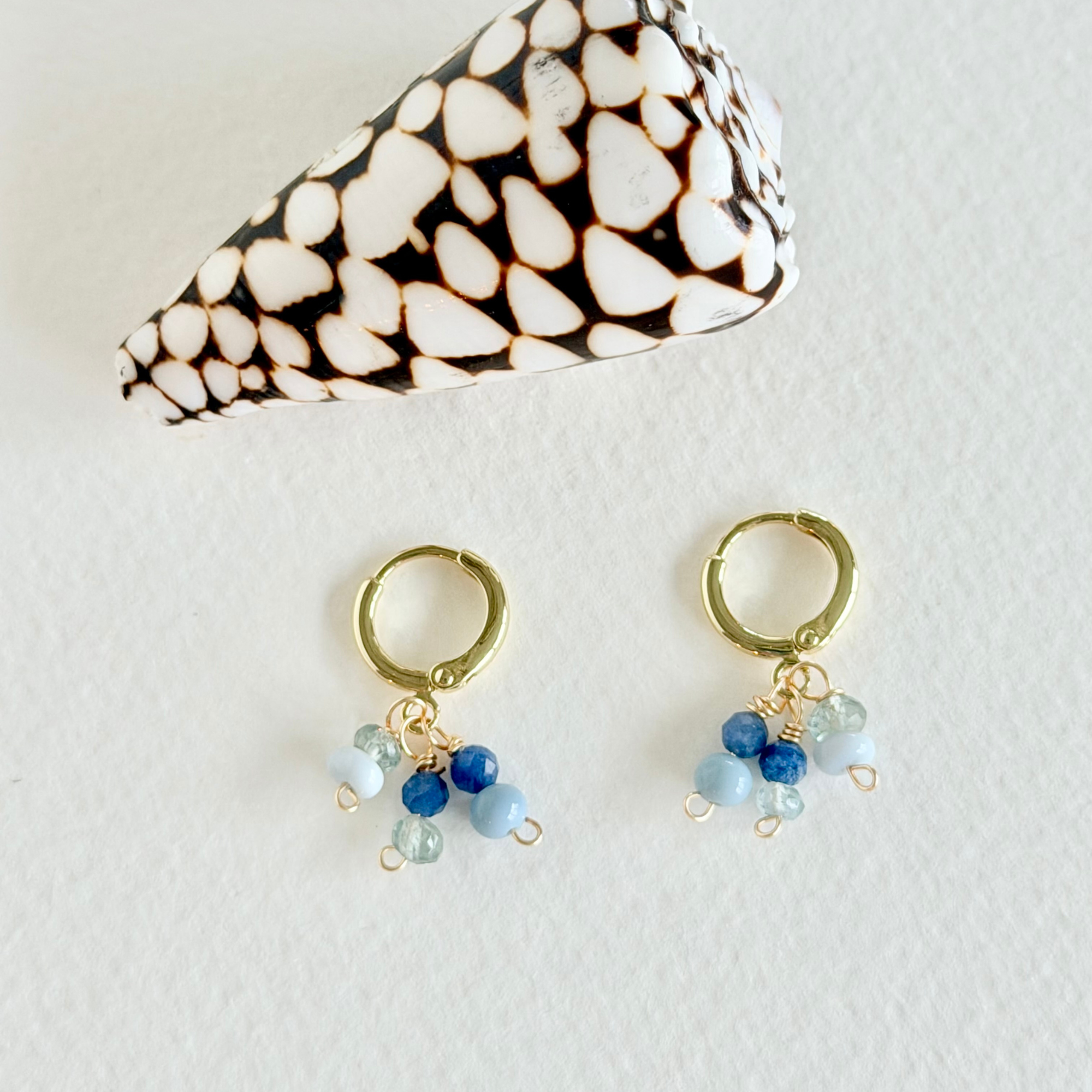 Gold hoop earrings with blue and green beads on a white background