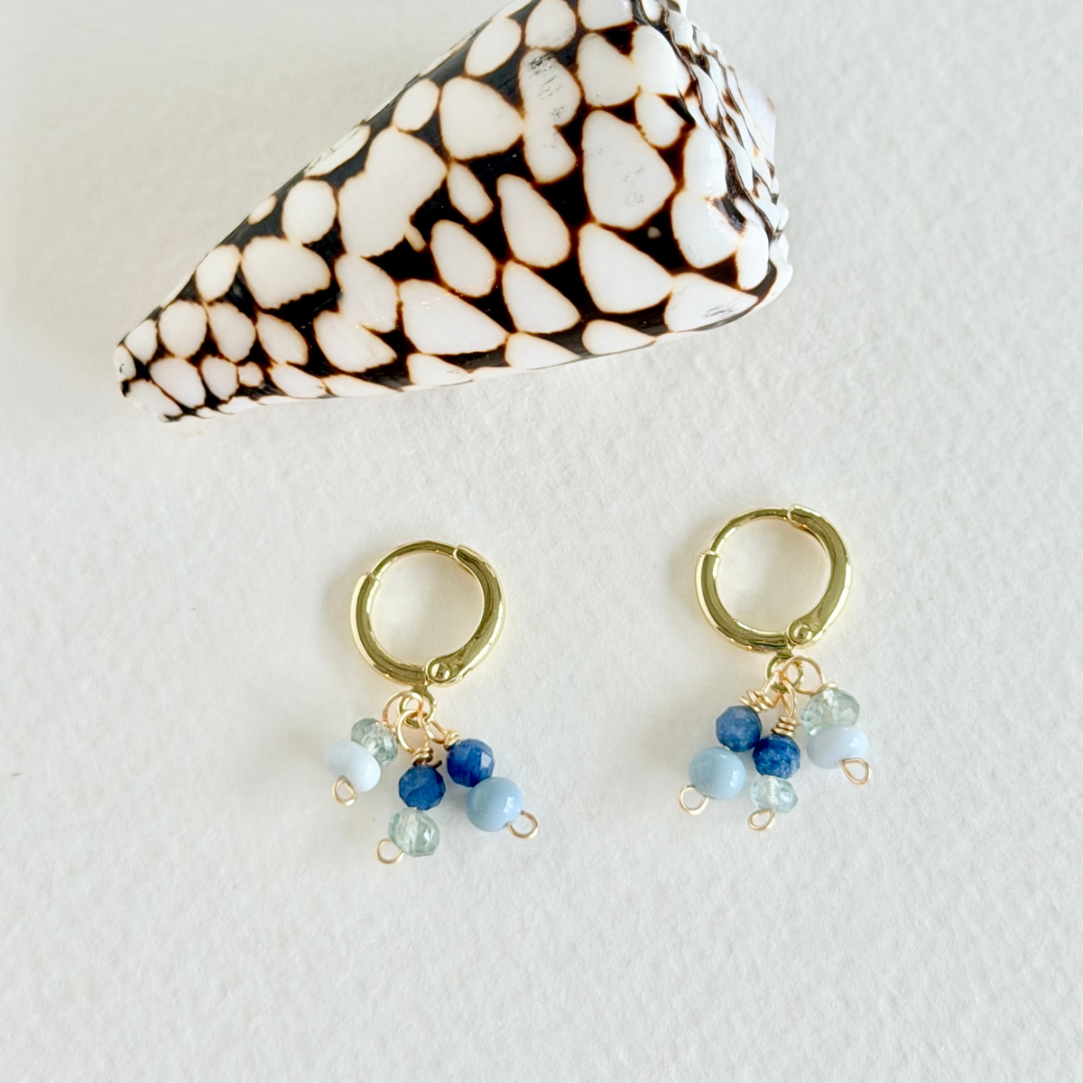 Gold hoop earrings with blue and green beads on a white background