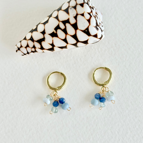Gold hoop earrings with blue and green beads on a white background
