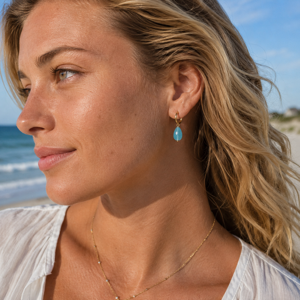 Woman wearing turquoise earrings on a beach