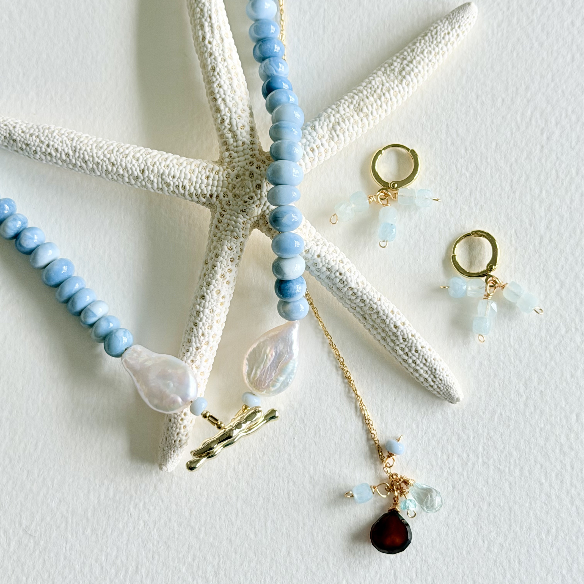Jewelry set with blue beaded necklace, earrings, and pendant on a starfish background