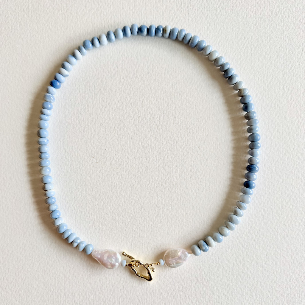 Necklace with blue beads and a gold clasp on a light background