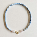 Necklace with blue beads and a gold clasp on a light background