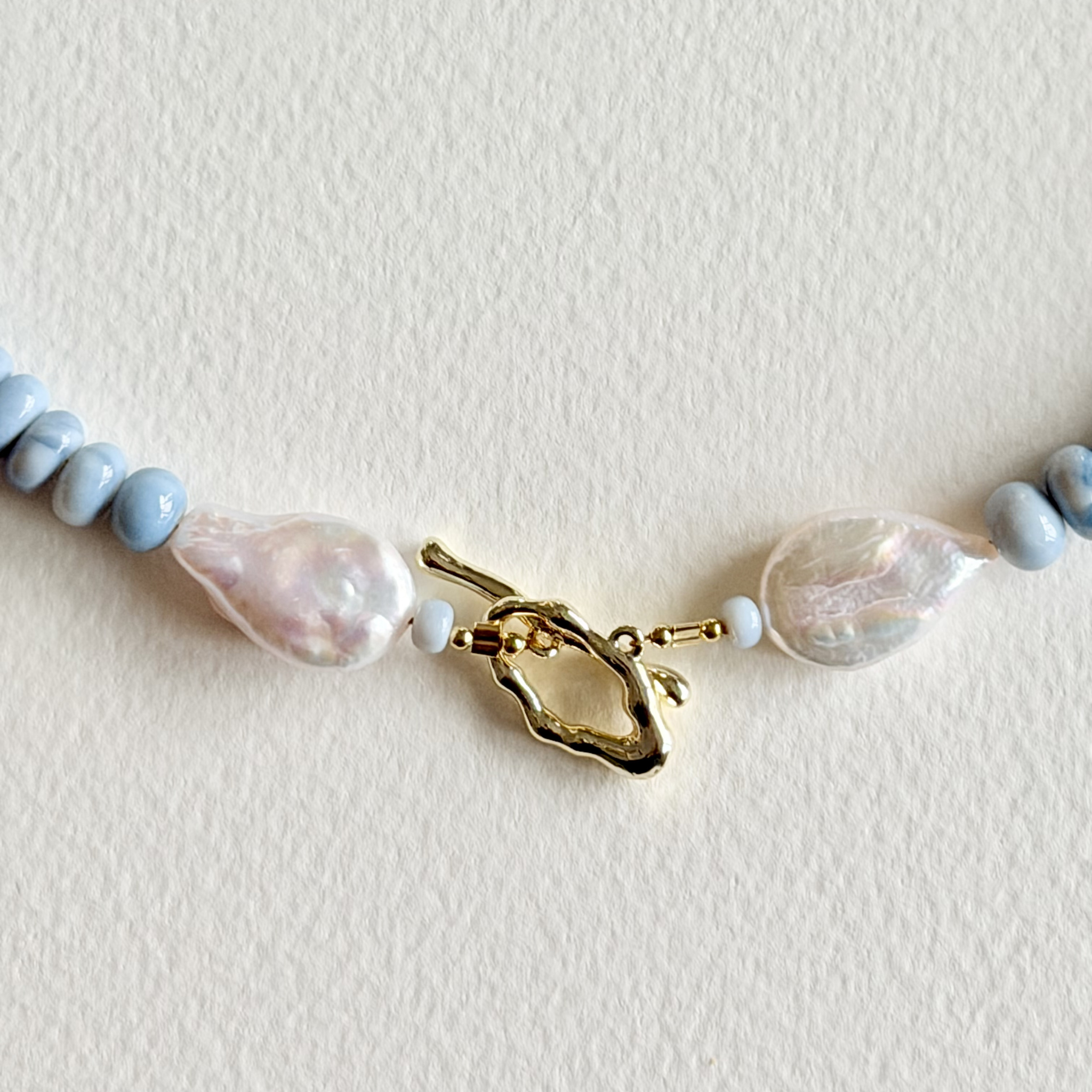 Necklace with pearls and a gold clasp on a light background