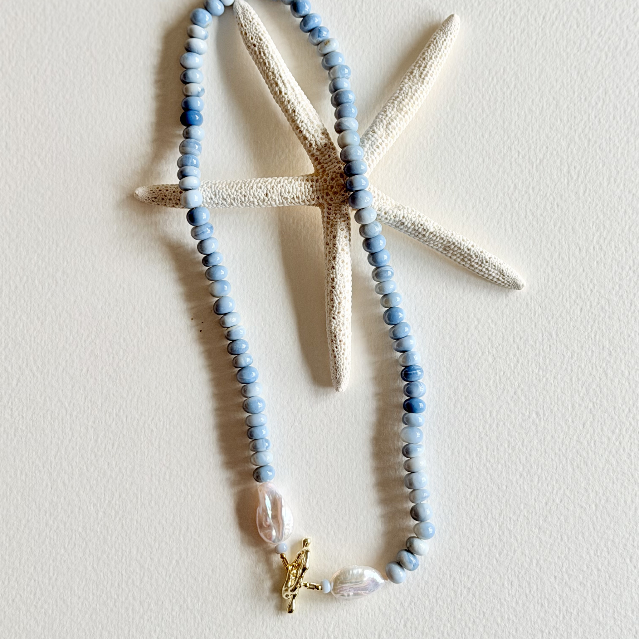Necklace with blue beads and a starfish charm on a white background