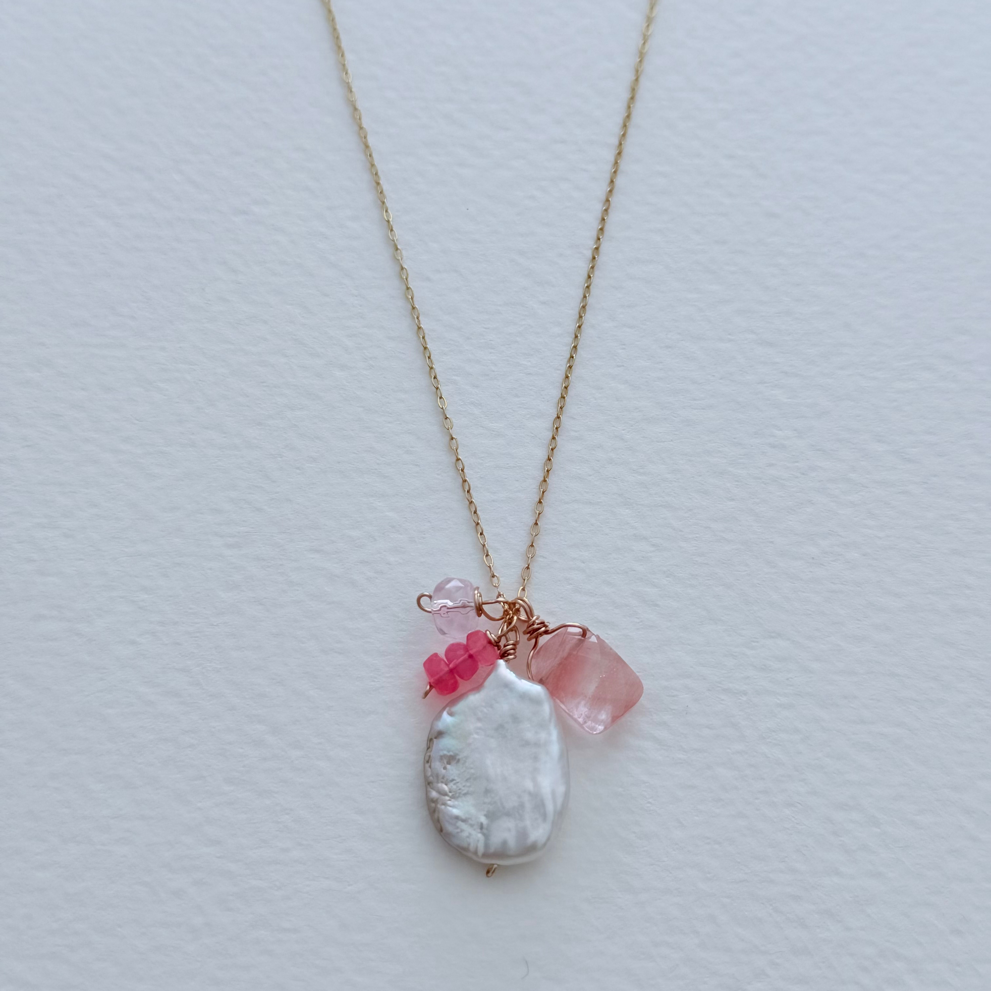 Necklace with a pearl pendant and pink beads on a light gray background