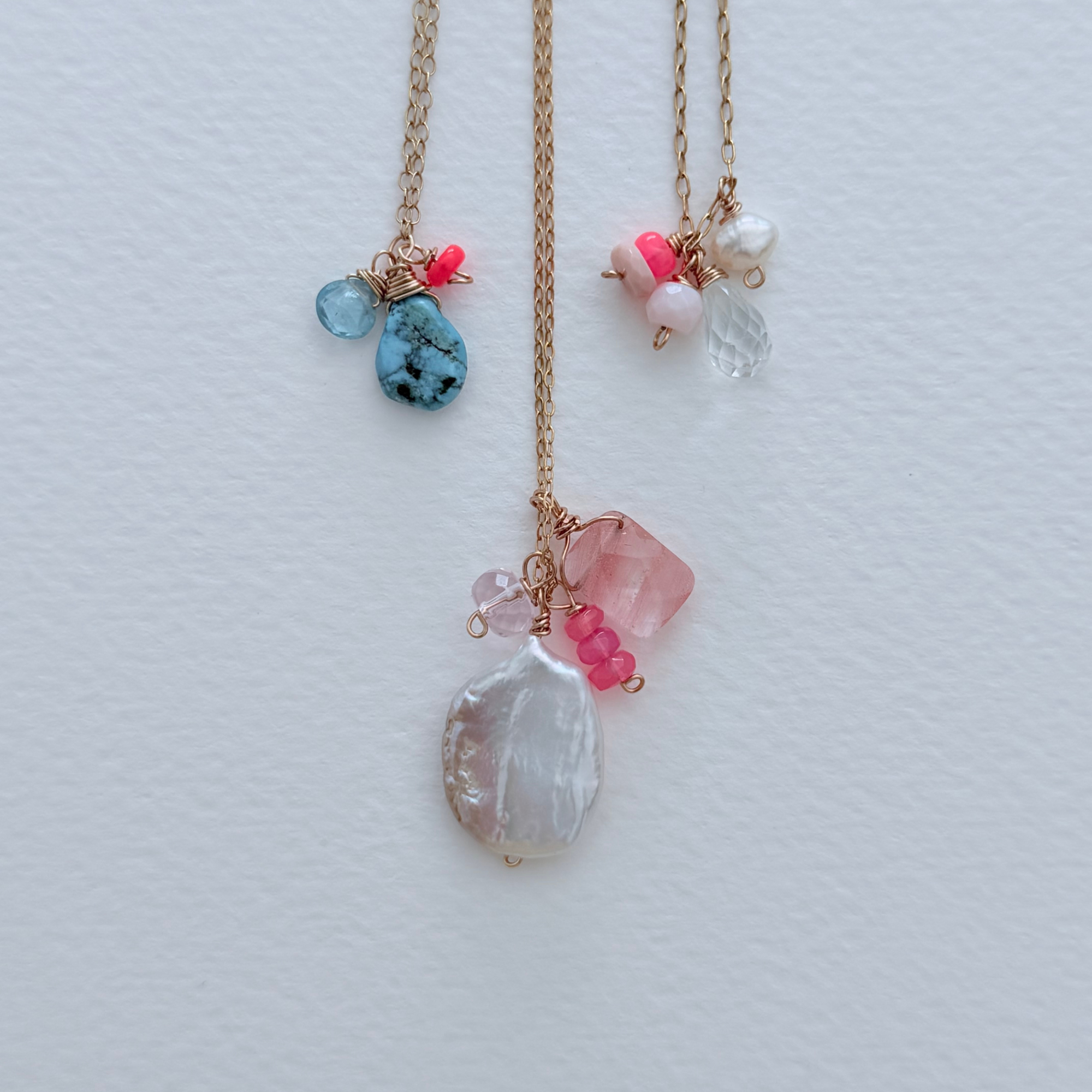 Two gold necklaces with colorful gemstones on a light gray background