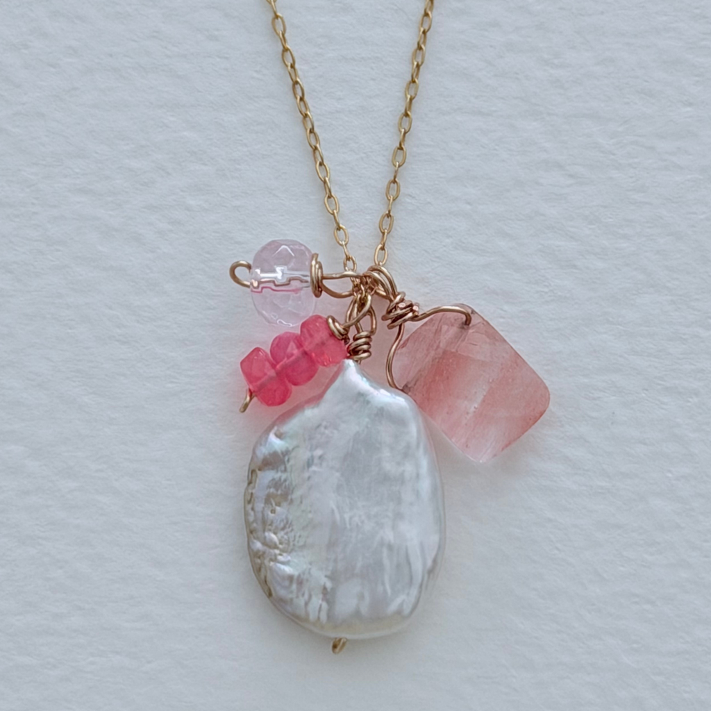 Necklace with pink and opal pendant on a light gray background