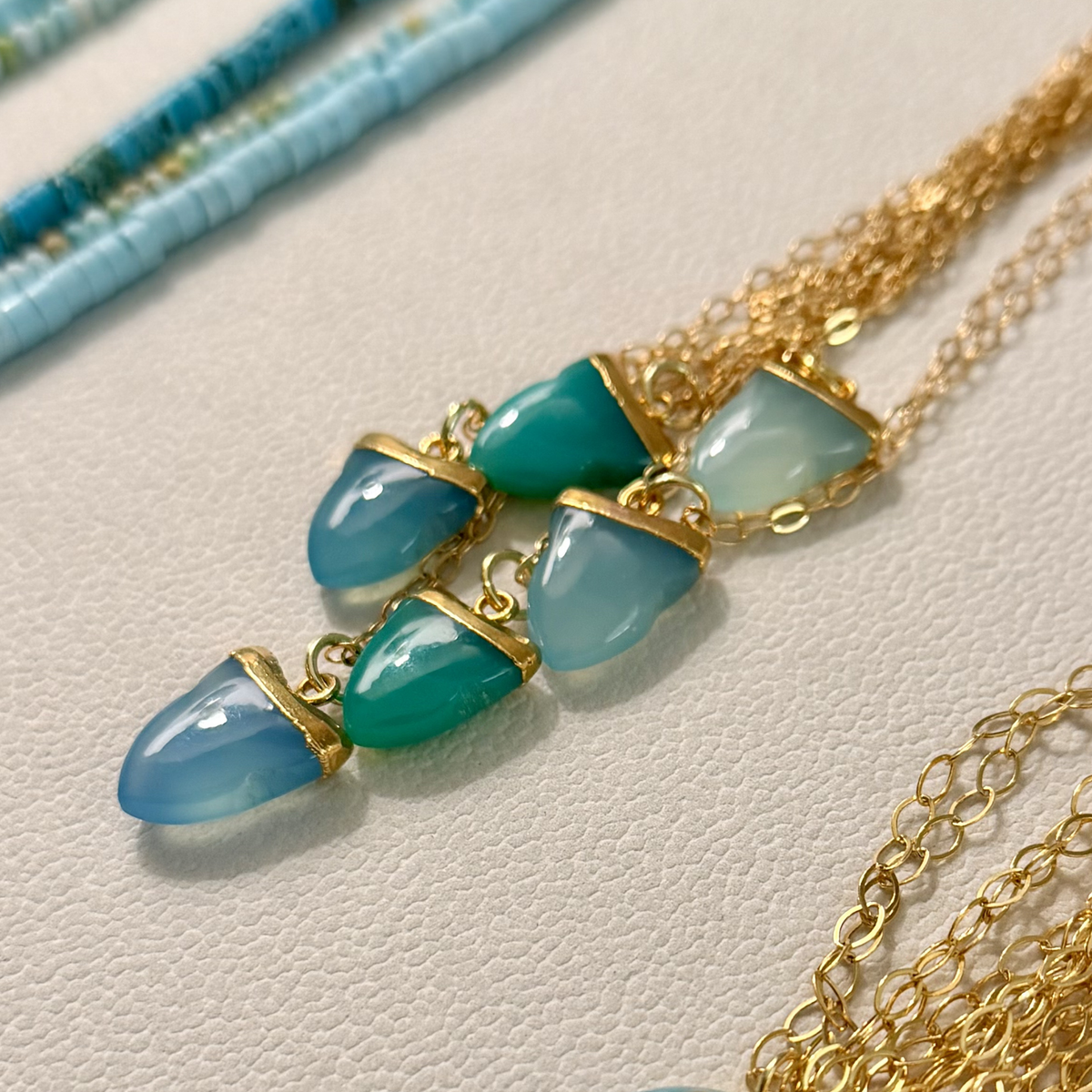 Necklace with blue gemstones and gold chain on a light background