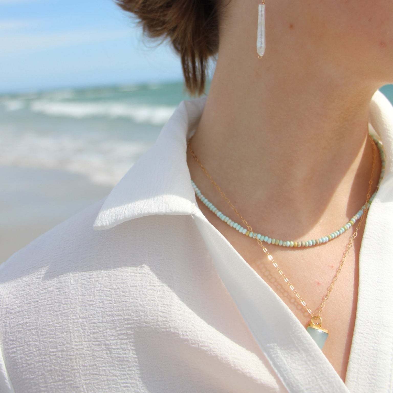 Person wearing earrings with a beach in the background