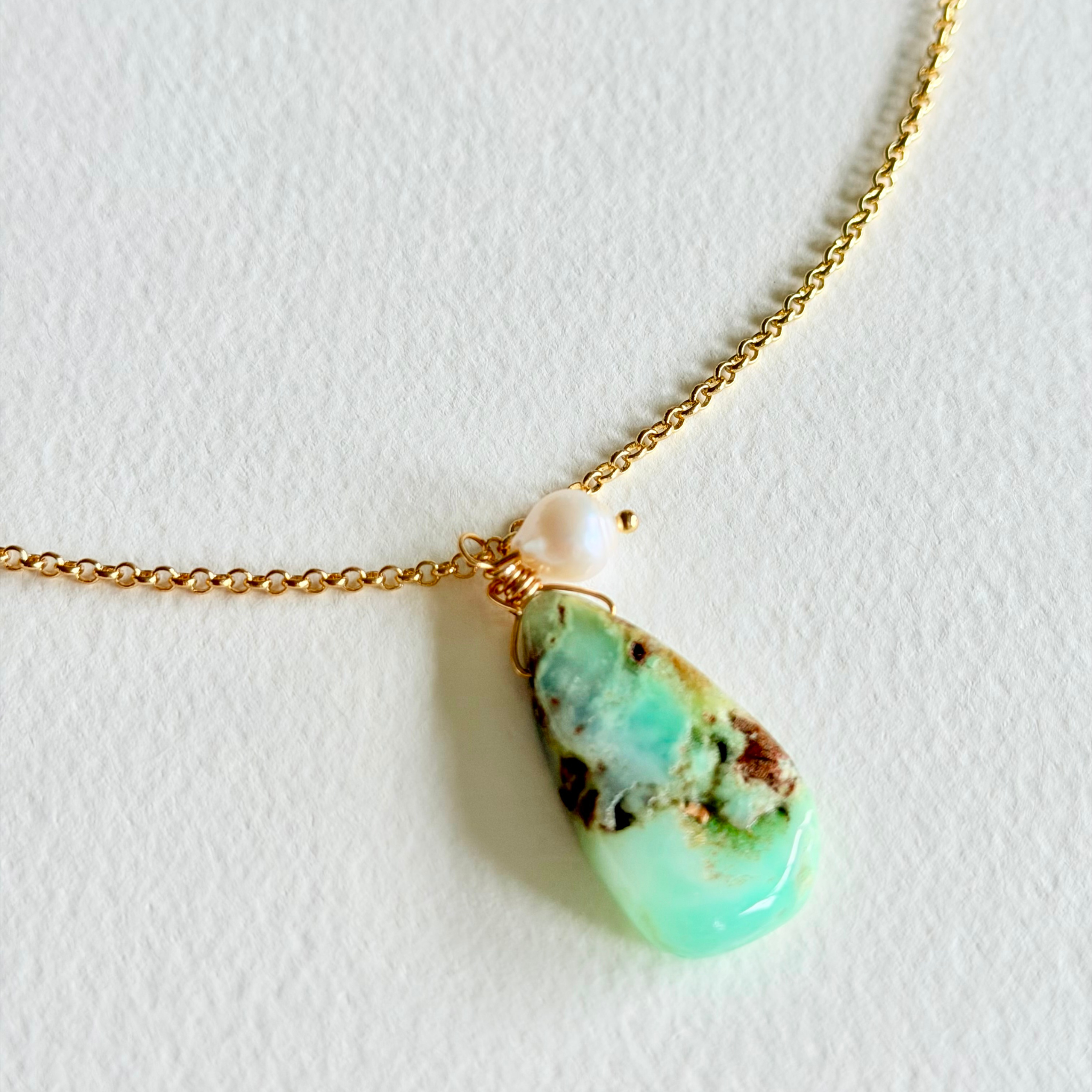 Necklace with a turquoise pendant and pearl on a light background