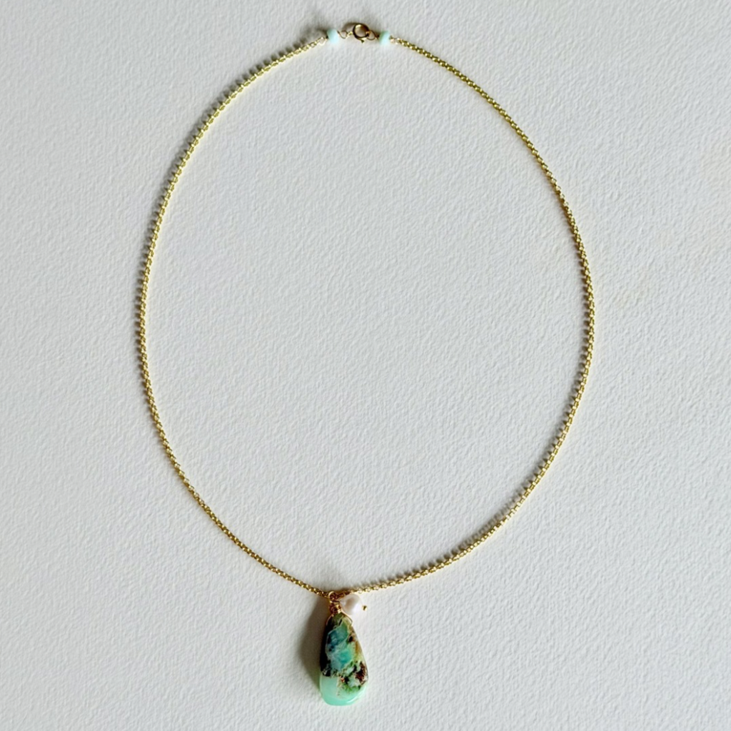 Necklace with a green pendant on a light gray background