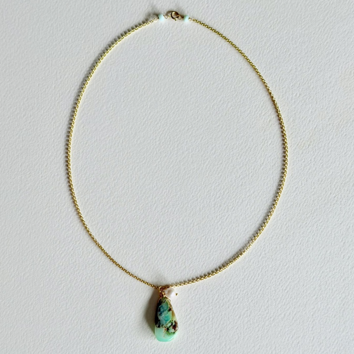 Necklace with a green pendant on a light gray background