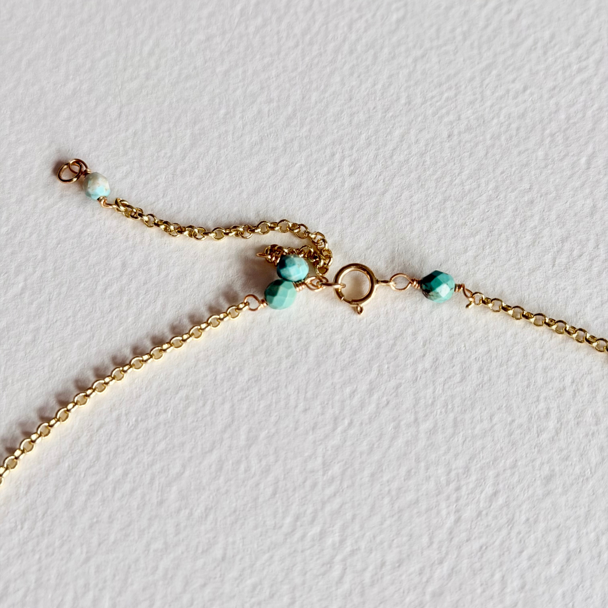 Gold bracelet with turquoise beads on a light background