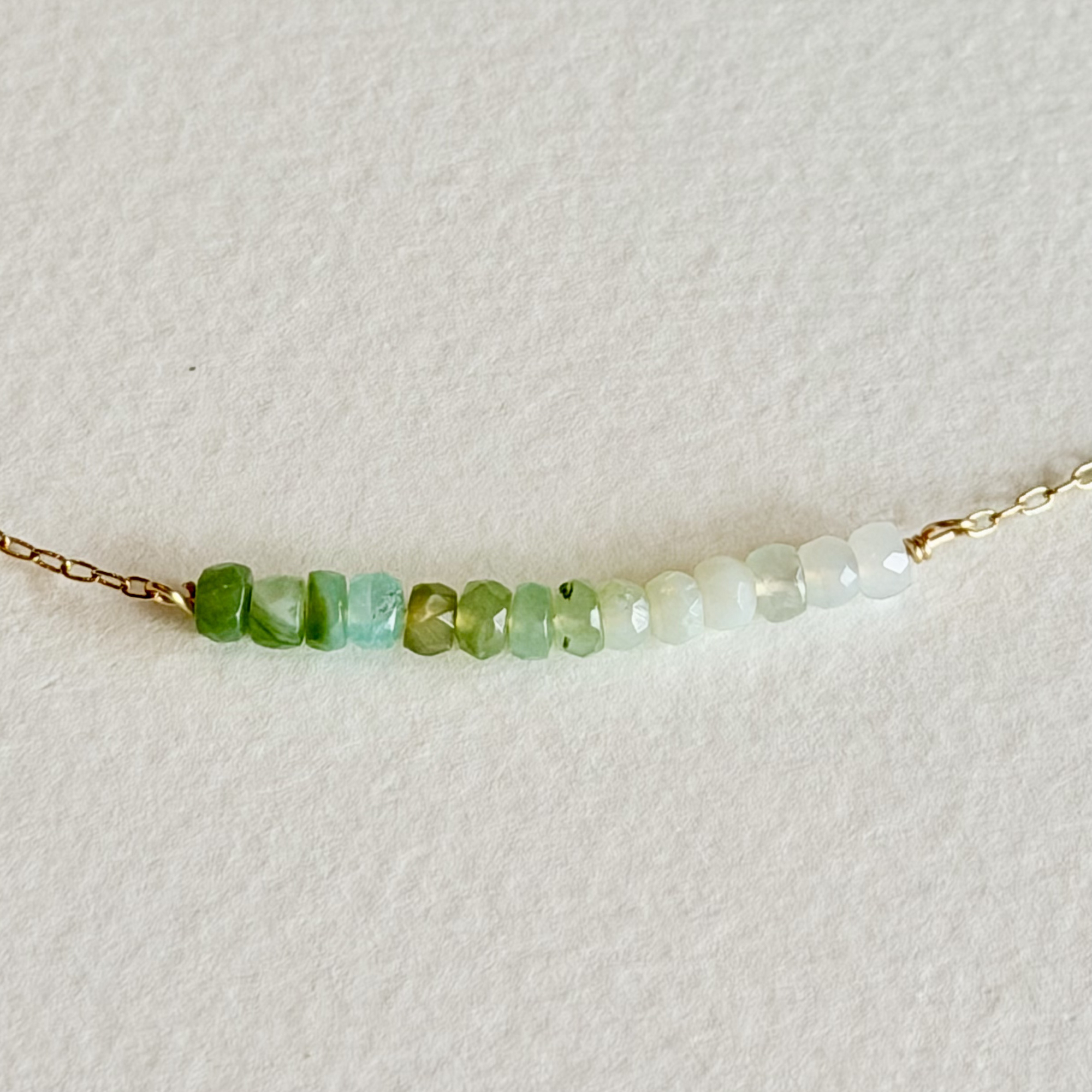 Necklace with green and white beaded chain on a light background