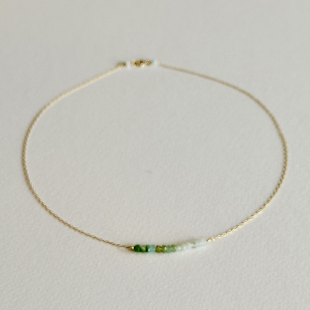 Necklace with green and white beads on a light gray background