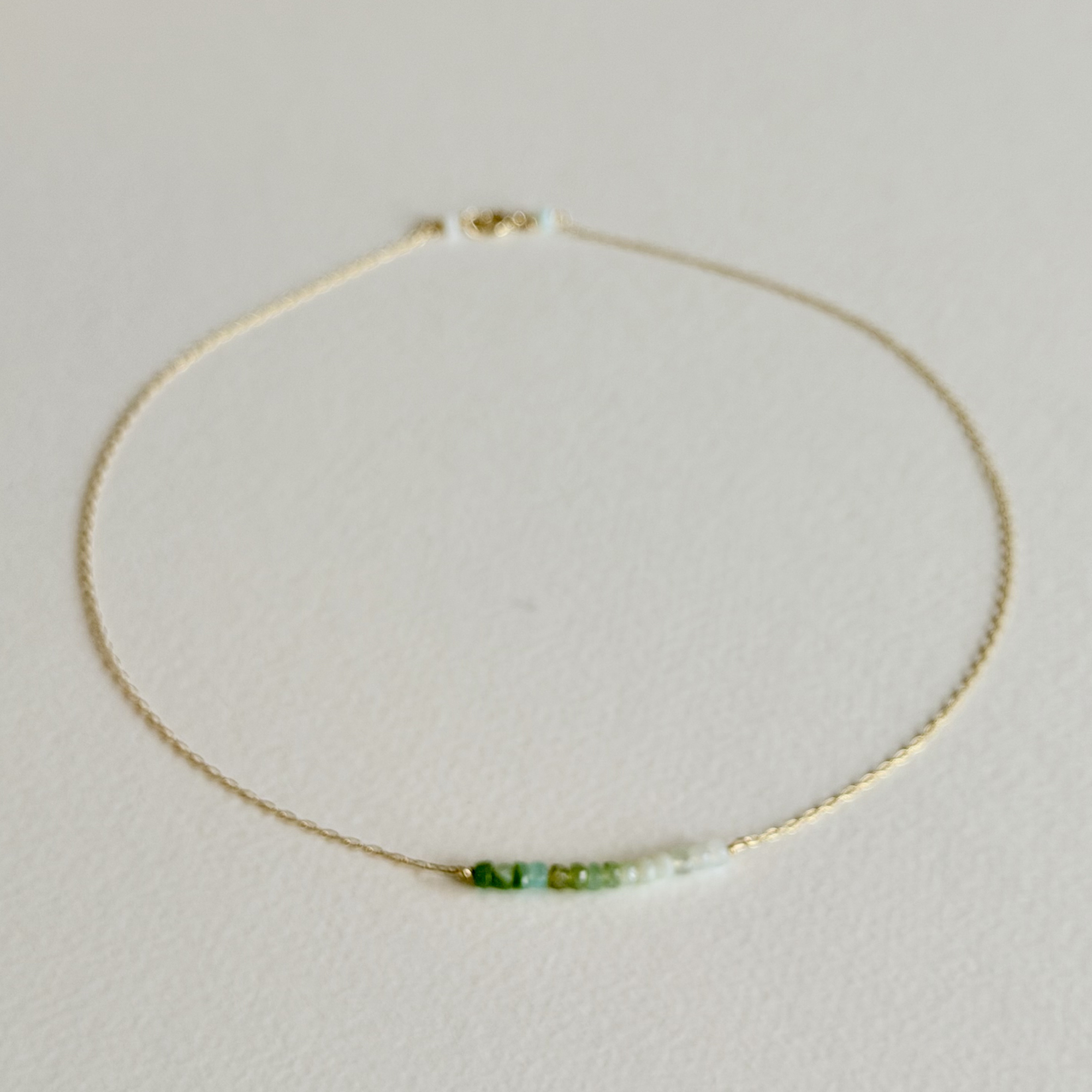 Necklace with green and white beads on a light gray background