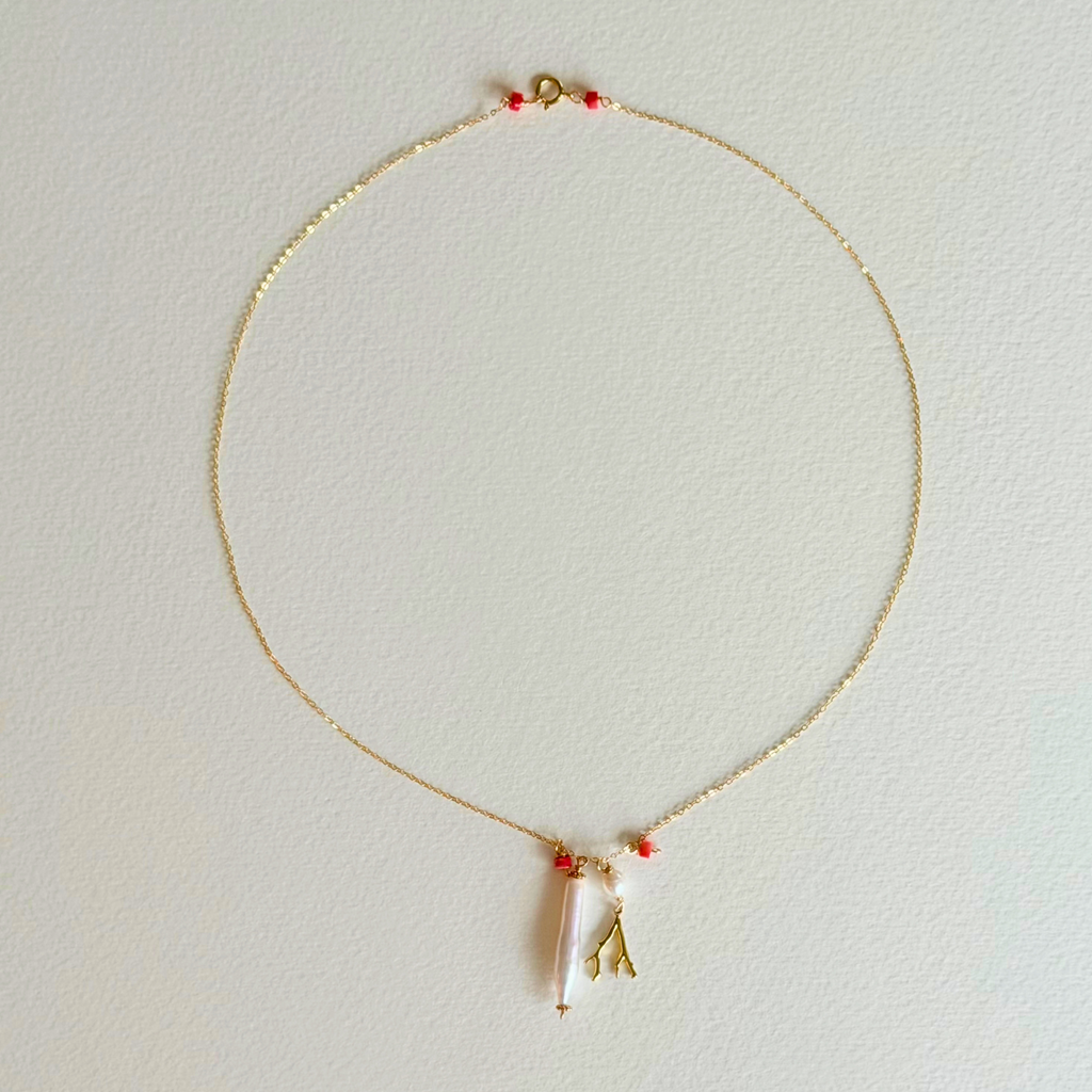 Delicate necklace with a small pendant on a light gray background