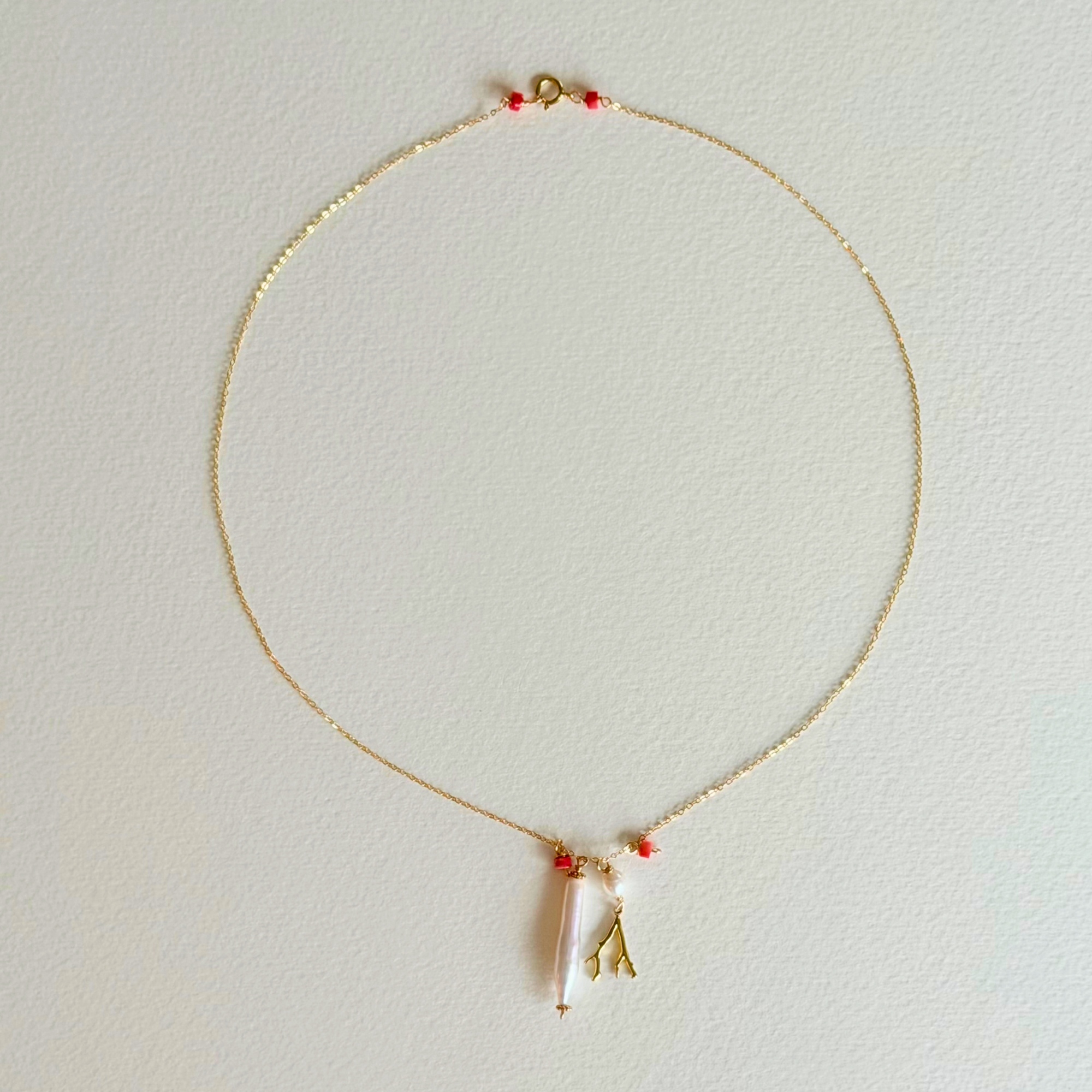 Delicate necklace with a small pendant on a light gray background