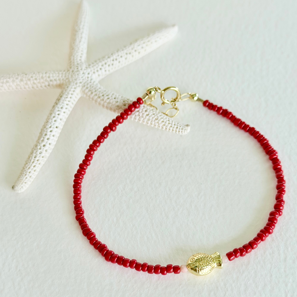 Red beaded bracelet with a gold clasp on a white background