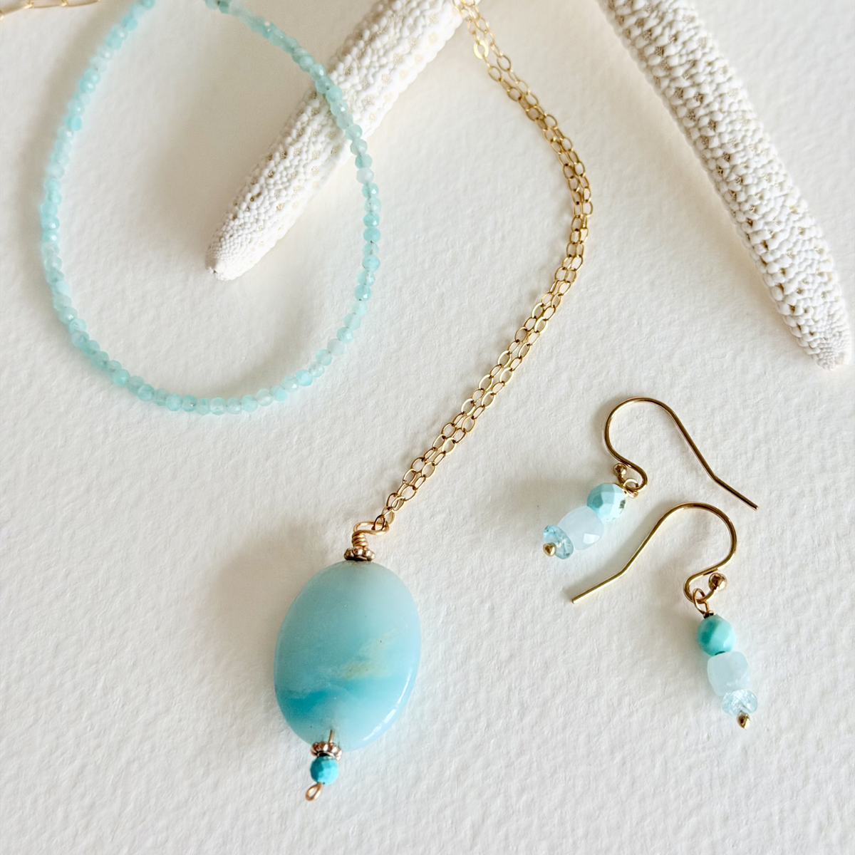 Turquoise beaded necklace, bracelet and earrings on a textured white surface