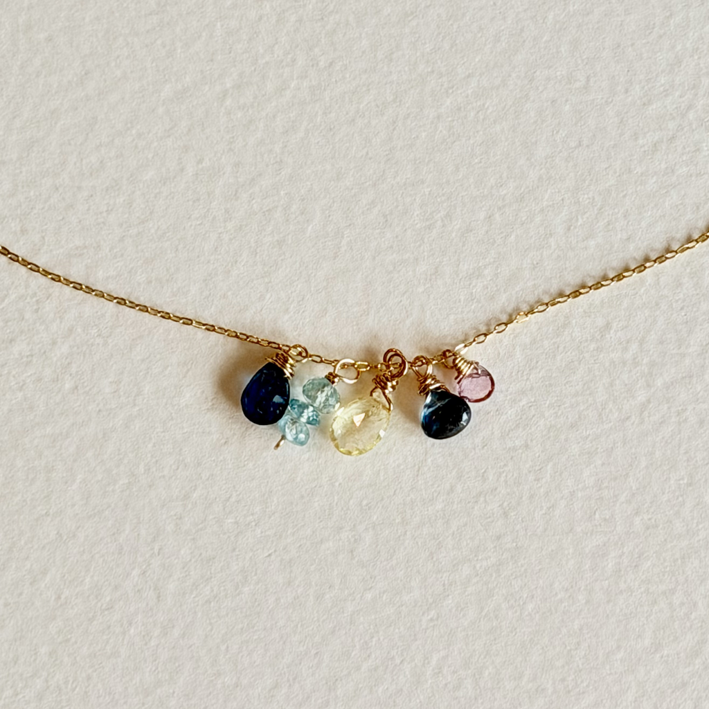 Delicate gold necklace with colorful gemstones on a light background