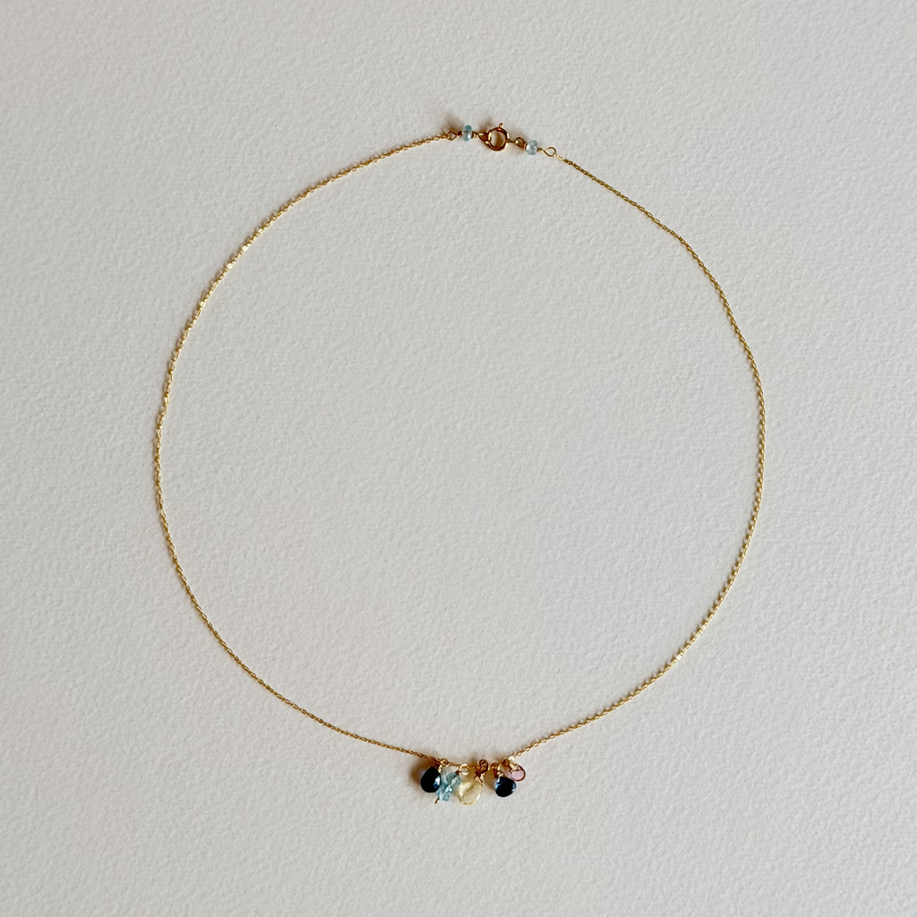 Gold necklace with colorful beads on a light gray background