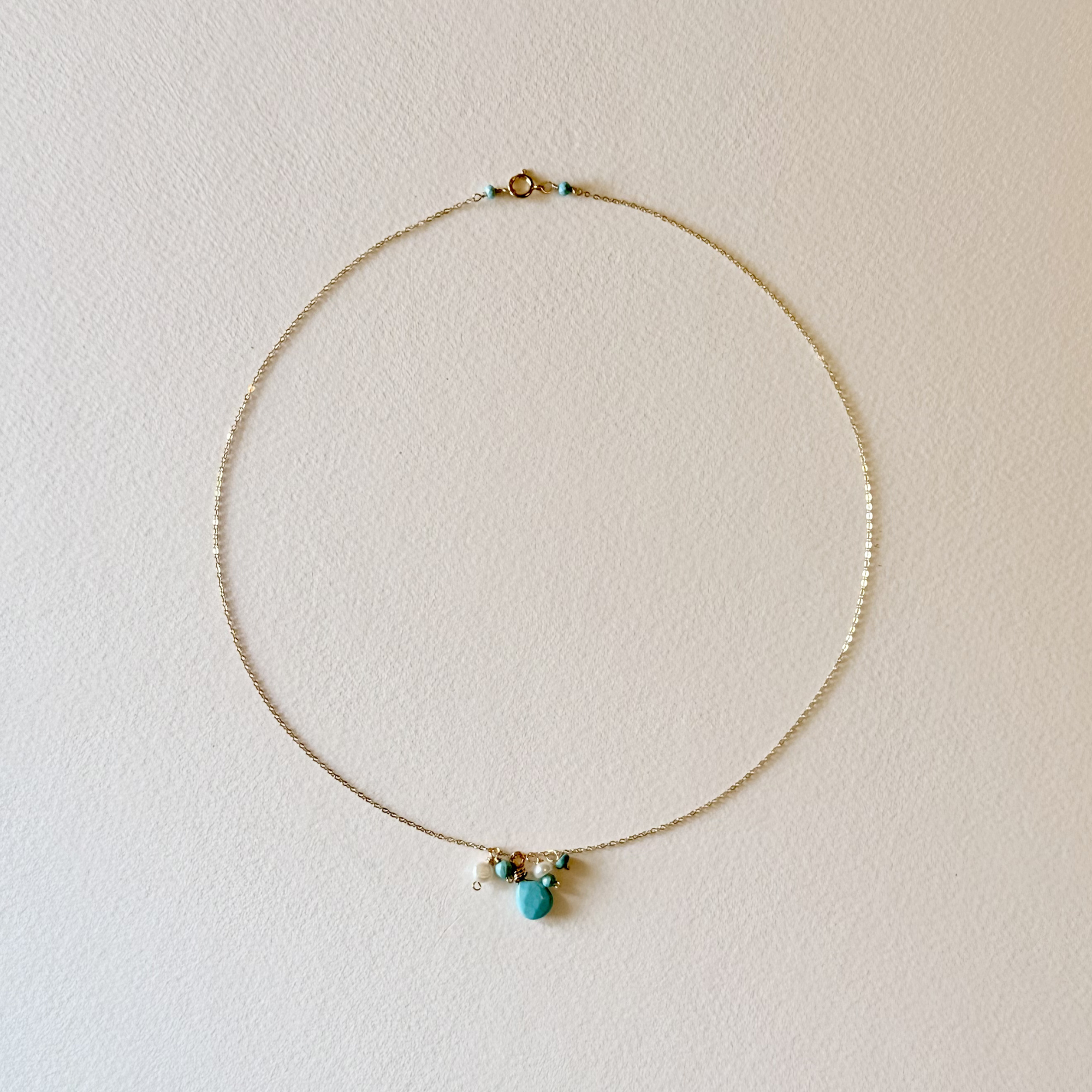 Dainty gemstone cluster necklace featuring turquoise and pearl charms on dainty 14k gold filled chain