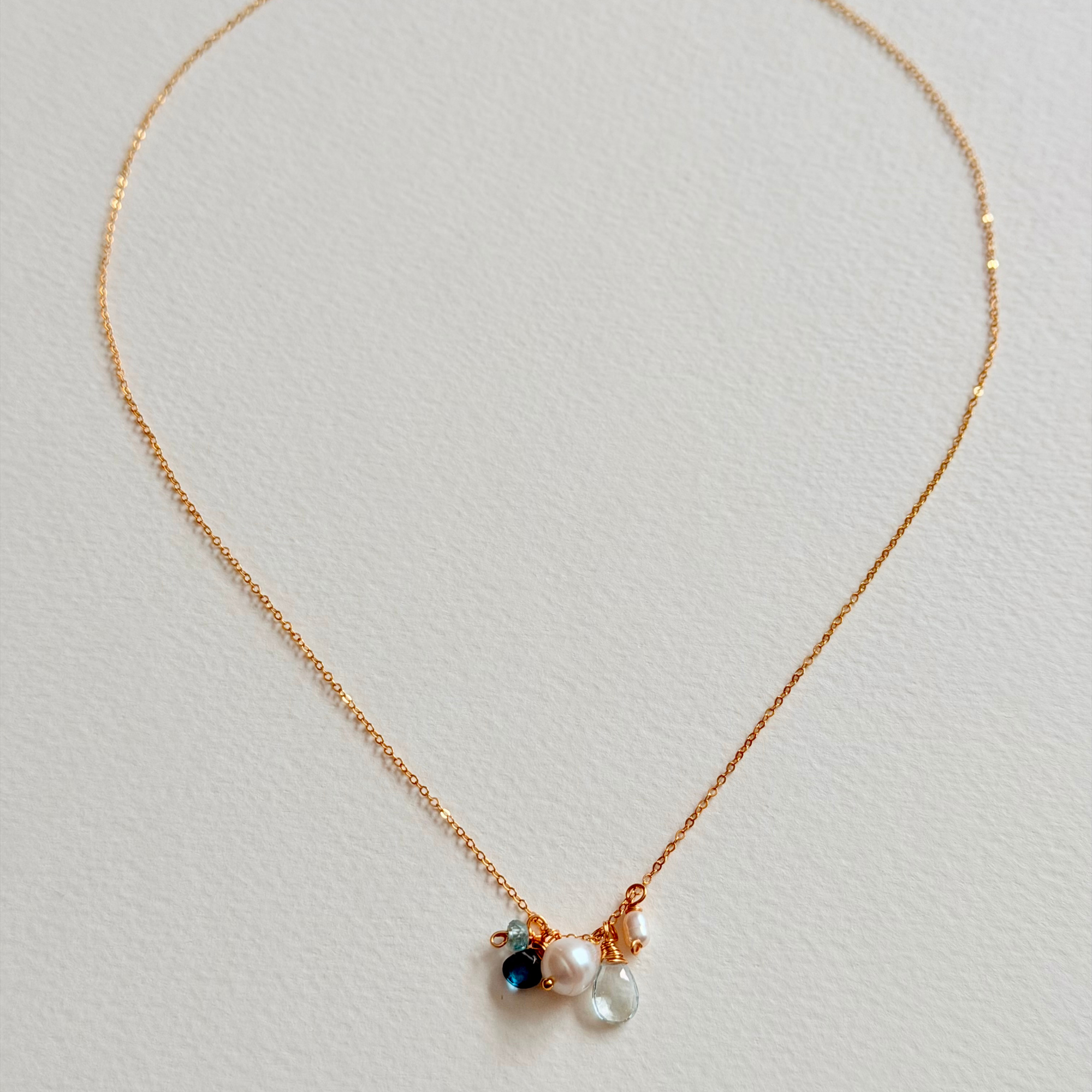 Delicate necklace with small pendants on a light gray background