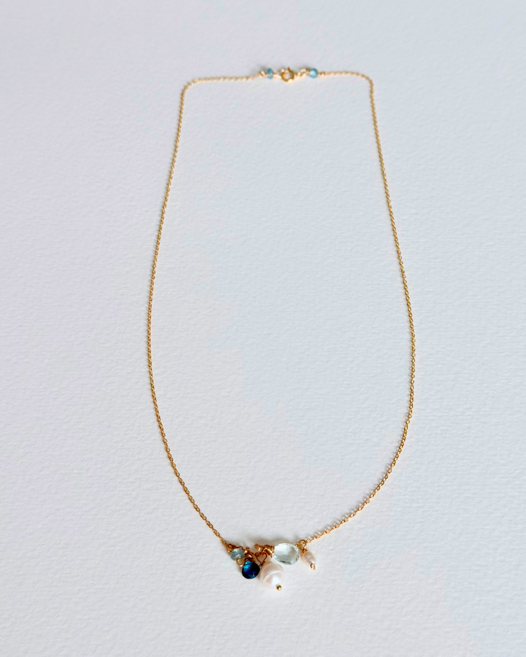 Gold necklace with gemstones on a light gray background