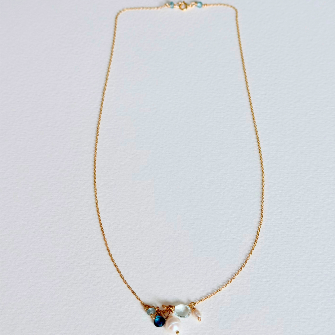 Gold necklace with gemstones on a light gray background